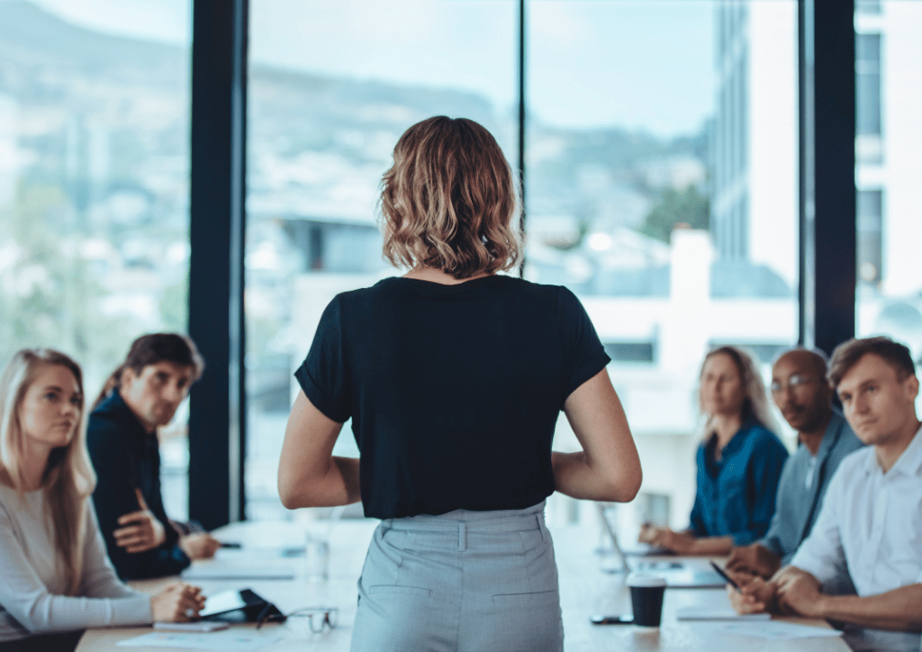 mulher em postura de liderança e gestão de pessoas sentadas ao seu redor - banco de imagens gratuitas - Plansul Consultoria